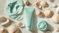 Mint green cosmetic cream jar and tube with seashells on sandy background. Natural skincare product flatlay with ocean elements and moisturizer.