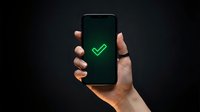 Caucasian male hand holding smartphone with green checkmark on dark screen against black background, representing approval, success, confirmation, mobile app verification, digital acceptance, online validation.