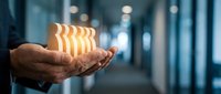 Young professional male hand holding glowing striped cube in modern office corridor, representing innovation, technology, and business solutions for corporate presentations.
