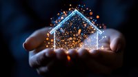 Glowing house silhouette with magical sparkles floating above cupped hands against dark background, representing home protection, dreams and real estate concept.