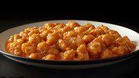 Crispy fried chickpeas coated in golden-brown seasoning served on white plate against dark background, ready for snacking or appetizer use.