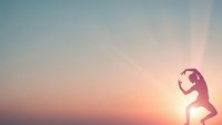 Young woman runner silhouette against dramatic sunset sky with warm orange and pink colors. Athletic female jogging at golden hour for fitness motivation.