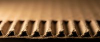 Corrugated cardboard texture with triangular fluted pattern showing natural brown kraft paper material structure for packaging and shipping applications.