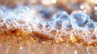 Delicate soap bubbles on golden surface create dreamy macro photography with soft bokeh lights and transparent spheres in artistic composition.