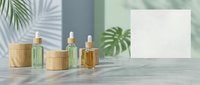 Natural skincare serum bottles with dropper caps on marble surface with tropical palm leaves and blank card for cosmetic branding mockup.
