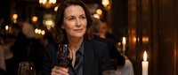 Elegant mature Caucasian woman enjoying red wine in upscale restaurant with warm candlelight ambiance for dining and hospitality marketing materials.