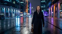 Young Asian woman in black coat standing on wet city street at night with colorful neon lights and modern buildings creating urban atmosphere for lifestyle content.
