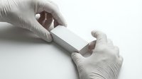 Medical professional hands in latex gloves holding blank test strip or diagnostic device for laboratory analysis and healthcare testing procedures.