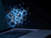 Glowing blue virus particles emerging from laptop screen against dark background, depicting digital infection or cyber threat concept.
