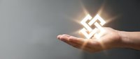 Hand holding glowing geometric cube symbol with bright light rays against gray background representing innovation, technology solutions and digital transformation.