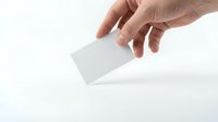 Hand holding blank white business card on isolated white background, suitable for branding, corporate identity, and marketing mockup designs.