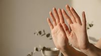 Two open palms raised in protective gesture against domestic violence with shadow silhouettes on wall background representing safety and defense.