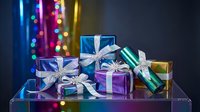 Colorful wrapped gift boxes with silver ribbons and bows arranged on transparent surface against festive bokeh lights background for holiday celebrations.
