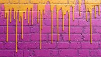 Vibrant yellow paint drips flowing down textured pink brick wall creating urban street art graffiti effect for creative design projects.