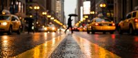 Rainy city street at night with glowing lights reflecting on wet asphalt, yellow taxis, and a pedestrian with umbrella in the background.