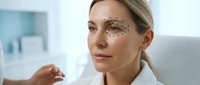Middle-aged Caucasian woman with facial mapping dots for cosmetic procedure planning in modern medical clinic setting for aesthetic treatment consultation.