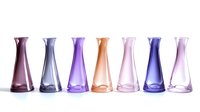 Collection of colorful glass vases in purple, pink, orange and blue tones arranged in row on white background for home decor and interior design projects.