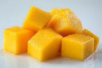Fresh ripe mango cut into juicy cubes with water droplets on bright surface, macro food photography showing tropical fruit texture and vibrant color.