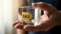 Businessman holding transparent glass cube with golden sale label inside, representing business deals, marketing promotions and commercial opportunities.