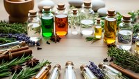 Collection of essential oil bottles with herbs and spices on wooden surface for aromatherapy, natural wellness and holistic healing treatments.