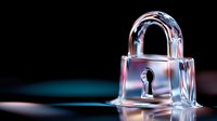 Crystal clear glass padlock with keyhole on reflective surface against dark background, dramatic lighting creates modern security concept for data protection and privacy.