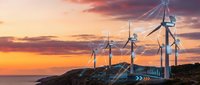 Wind turbines generating renewable energy on coastal hillside during dramatic sunset with orange and purple sky colors creating sustainable power landscape.