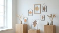 Autumn leaf botanical prints in frames displayed on wooden pedestals with dried pampas grass creating cozy seasonal home decor for living spaces.