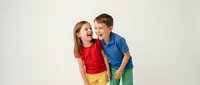 Happy Caucasian children boy and girl laughing together in colorful casual clothing on white background isolated for design projects.