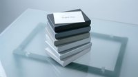 Stack of gray gift boxes with a thank you card on top, arranged on a glass surface, conveying gratitude and elegant minimalist style.