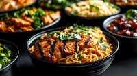 Delicious Asian noodle bowls with grilled meat, fresh herbs and colorful vegetables served in black ceramic dishes for restaurant menu and food delivery.