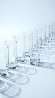 Row of empty clear glass tumblers casting circular shadows on white surface for beverage service and hospitality industry applications.