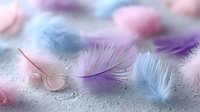 Soft pastel feathers in pink, blue and purple tones scattered on textured surface creating dreamy ethereal composition for spa wellness and relaxation themes.