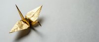 Golden origami crane with textured metallic finish on neutral background for luxury design projects and decorative arts applications.
