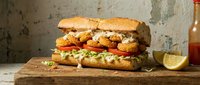 Crispy fried chicken sandwich with fresh lettuce and tomato on rustic wooden board. Gourmet fast food meal ready to serve for restaurant menu photography.