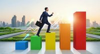 Professional businessman in suit climbing colorful bar chart steps representing growth and success with modern city skyline background at sunrise.
