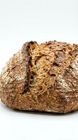 Freshly baked artisan multigrain bread loaf with seeds and nuts on white background, healthy organic bakery product for food photography and cooking content.