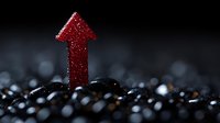 Red glittery arrow pointing upward emerging from dark textured surface with bokeh light effects, symbolizing growth, success and positive business direction.