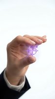 Businessman hand holding glowing purple target crosshair symbol representing precision, focus and strategic goal achievement in corporate environment.