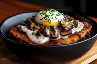 Crispy breaded chicken cutlet topped with sauteed mushrooms, creamy white sauce, fresh herbs and poached egg with runny yolk served in black bowl.