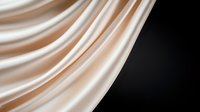 Elegant cream-colored silk fabric with soft folds and gentle waves creates dramatic contrast against dark background, showcasing luxurious textile texture and flow.