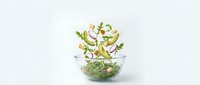 Fresh green salad leaves flying and falling into transparent glass bowl on white background for healthy eating and cooking concepts.