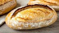 Fresh baked artisan bread loaves with golden crust on rustic wooden surface, perfect for bakery marketing, food photography and culinary designs.