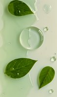 Fresh green leaves with pure water drops and transparent gel substance on light background, natural skincare concept for cosmetic product advertising.