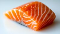 Fresh raw salmon fillet with distinctive orange-pink color and white marbling pattern on light background, macro food photography for culinary and restaurant use.