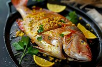 Fresh whole red snapper seasoned with herbs, garlic, and lemon slices, served on black cast iron pan with fresh parsley garnish, ready for Mediterranean style cooking.
