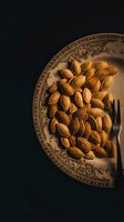 Roasted almonds served on ornate vintage plate with decorative patterns against dark background for culinary and food photography projects.