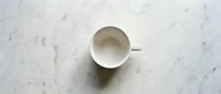 Empty white ceramic cup on marble surface, overhead view for minimalist design, branding, and lifestyle content.