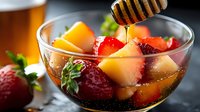 Refreshing summer beverage with fresh strawberries, peaches, and honey drizzle in a glass bowl, perfect for food and drink photography, recipes, and culinary content.