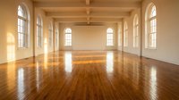 Empty spacious hall with polished wooden floor, arched windows, and natural light, suitable for events, studios, galleries, or commercial interiors.