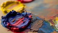 Colorful oil paint palette with mixed pigments and brush strokes on artist canvas. Creative art supplies for painting and artistic expression projects.